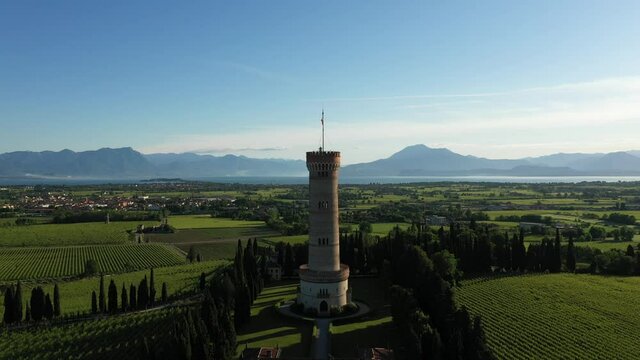 Fly up along the Tower of San Martino della Battaglia. Italian vineyards. Tower of San Martino, in the background of Lake Garda, early in the morning.