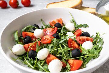 Mozzarella salad with tomatoes black olives arugula and olive oil. dish of Italian Greek cuisine. Healthy eating