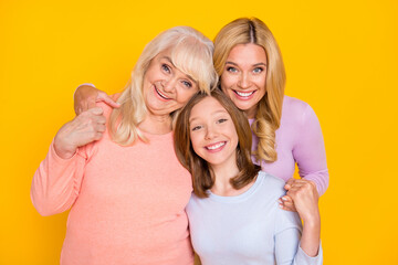 Photo of nice optimistic three woman grand mom daughter hug wear pastel cloth isolated on yellow...