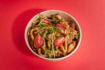 Wok with egg noodles, chicken, carb and spicy carrots in a creamy curry sauce. In a food delivery plate. Close-up. view from above. Isolated.