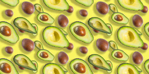 Seamless pattern of fresh ripe green avocado fruit halves with bones isolated on yellow background. Top view. Banner. Flat lay composition. Creative summer food background