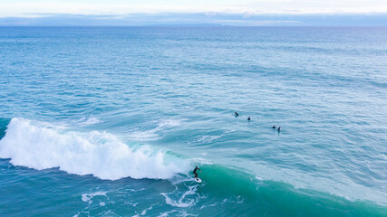 Aerial drone view of surfers riding perfect Atlantic waves in the south coast of Spain, Caños de...