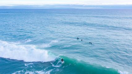 Aerial drone view of surfers riding perfect swell waves in the beach of Los Caños de Meca in Cadiz, South Spain