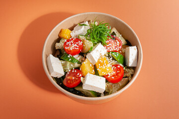 Salad with tofu cheese and vegetables. In a food delivery plate. Close-up. View from above. Isolated.