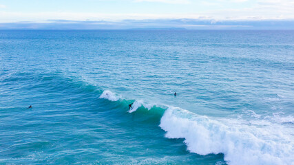Aerial drone view of surfers riding perfect Atlantic waves in the south coast of Spain, Caños de...