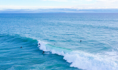 Aerial drone view of surfers riding perfect swell waves in the beach of Los Caños de Meca in...