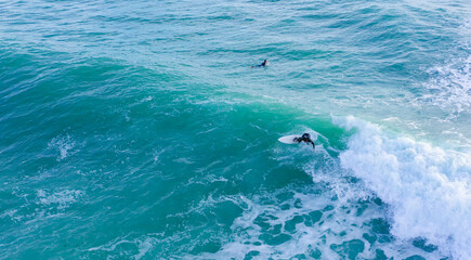 Naklejka premium Aerial drone view of surfers riding perfect Atlantic waves in the south coast of Spain, Caños de Meca near Trafalgar