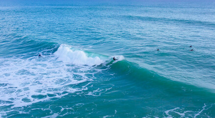 Aerial drone view of surfers riding perfect Atlantic waves in the south coast of Spain, Caños de...