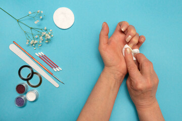 Removing nail polish. Top view floral composition. Accessories for manicure and nail care on a colored background.
