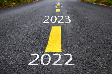 Number of 2022 to 2025 on  asphalt road with yellow line marking on road surface. Happy new year concept and productive idea