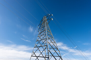 Photography of a High voltage tower, power line with electric cables and insulators against a blue...