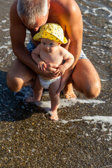 dad and baby son are resting on the sea on the beach in the summer together on the shore on the pebbles