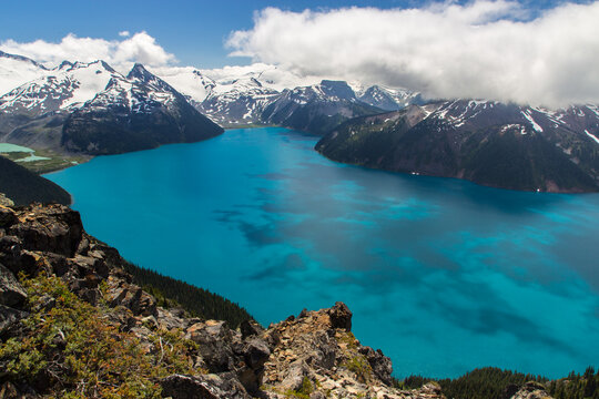 Turquoise and blue waters of Garibaldi Lake with majestic mountains around covered with snow and with blue sky and white clouds around, Photo from hike Panorama ridge trail, CANADA © vladimir