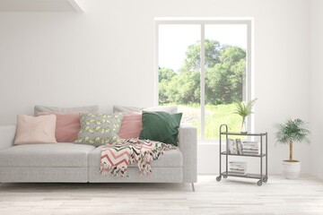 White living room with sofa and summer landscape in window. Scandinavian interior design. 3D illustration