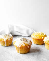 Lemon Poppy Seed Muffins on a concrete worktop and bright grey background.