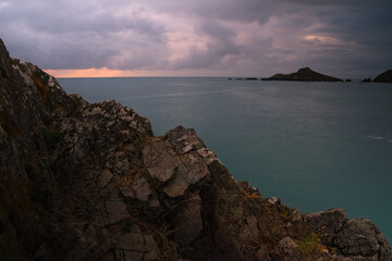 Mer et rochers en pose longue sous un ciel nuageux