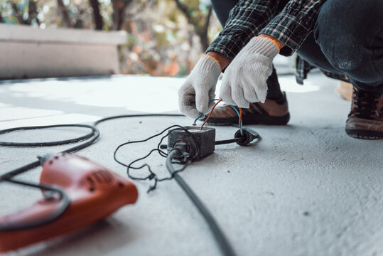 Hand Connecting Power Outlet To An Electric Tool No Electrical Plug Cause Electric Shock, Be Unaware Of Worker,  Work Accidents Electric Shock Of A Worker In The Workplace Concept.