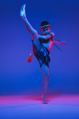 Young boy thai boxer training isolated on blue background in neon light.