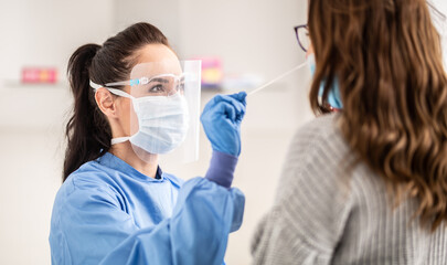 Female medical staff worker wearing protective equipment takes sample from nose of a patient to antigen test for coronavirus - obrazy, fototapety, plakaty