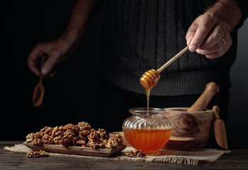 Man prepares a breakfast of walnuts and honey.