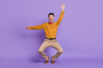 Fototapeta na wymiar Photo of adorable funny young guy dressed checkered shirt dancing rising arm isolated purple color background