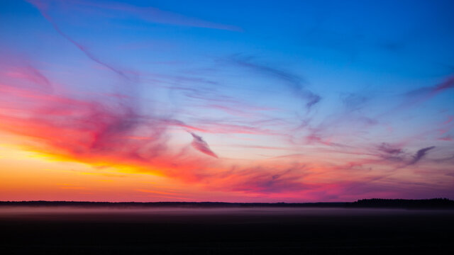 incredible colorful summer sunset over the field, unusual clouds of different shapes