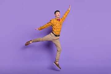 Fototapeta na wymiar Full length photo of cute sweet young guy dressed checkered shirt jumping arms sides isolated purple color background