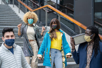 group of young people dancing in the city, social distancing and protection with facemask,...