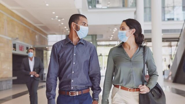 Multiethnic business people with face mask walking in office building and talking