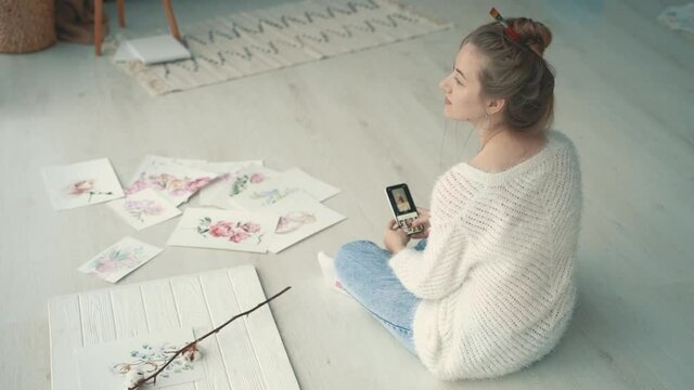 Young female creator taking photos of her illustrations