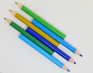 green and blue pencils, arranged diagonally in a herringbone pattern, on a white textured background