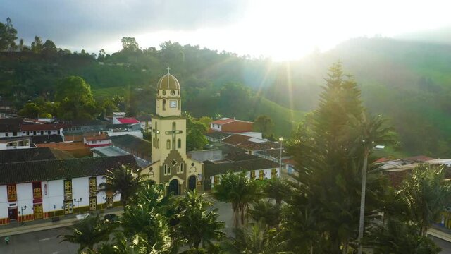 Aerial View of Catholic Church in Mountain Town with Dramatic Sun Flare
