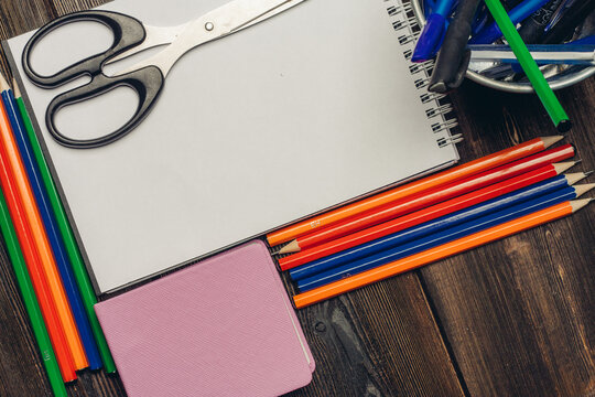 notepads colored pencils and stationery in a glass on a wooden table top view