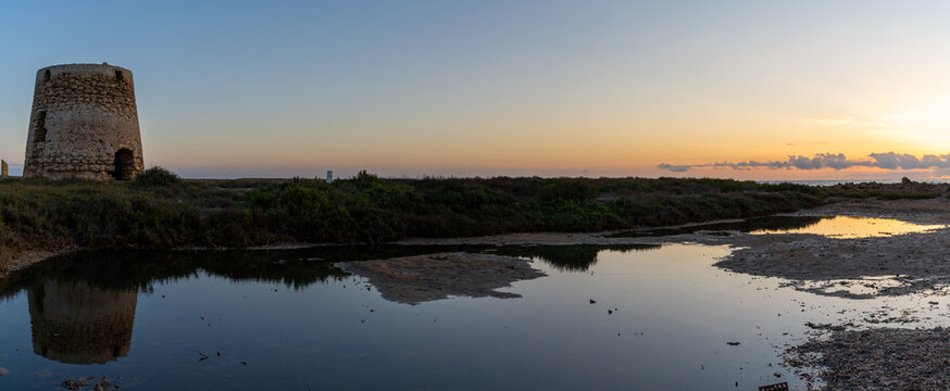 panorama view of old windmill ruins and tidal pools on the coast of Murcia at sunset