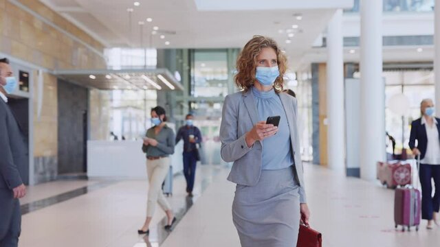 Businesswoman Wearing Face Mask And Checking Her Phone At Airport