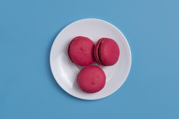 Red macarons on a plate on a blue background