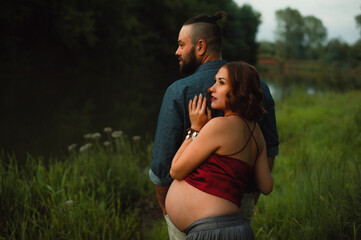 A pregnant couple contemplates nature on the banks of the river in the evening at regular time.