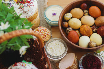 Fototapeta na wymiar Stylish easter eggs, homemade Easter bread, traditional Easter food in basket on rustic table
