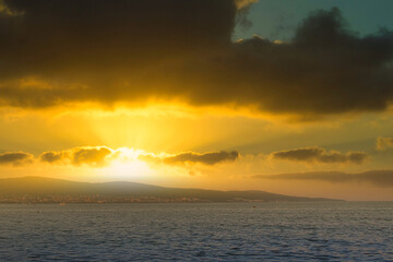 Still blue sea water under colorful evening cloudy sky