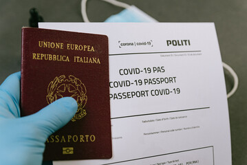 hand with latex gloves holding covid vaccine passport concept. travel and tourism during covid19 pandemic with restrictions and lockdown to stop spread the corona virus