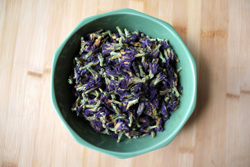 Herbal tea of purple flowers in green bowl.