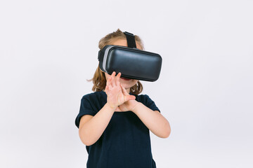 Little girl wearing virtual reality glasses with hands trying to touch something virtually, on white background