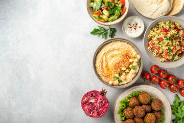 Middle eastern or arabic cuisines, falafel, hummus, tabouleh, pita and vegetables on a concrete background, view from above, copy space