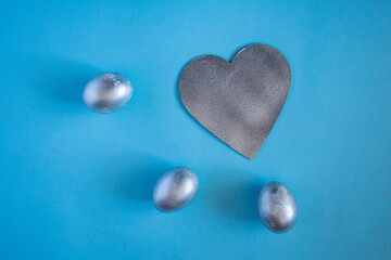 Silver eggs and decorative silver heart on delicate blue background. concept of rich Easter holidays, greeting cards and spring love.