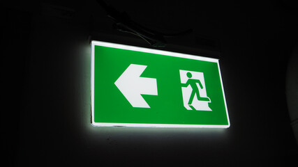 emergency fire exit sign direction to doorway in the building green color and narrow.
