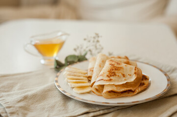 Pancakes with bananas and honey on white plate. Healthy breakfast food.
