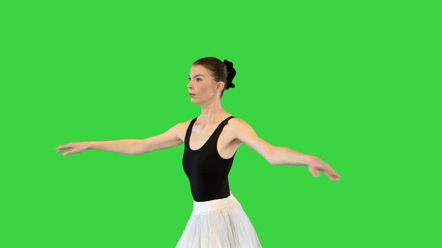 Ballerina in a romantic tutu and pointe ballet shoes training fouette on a Green Screen, Chroma Key.