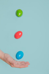 Hand catching flying colourd eggs, easter minimal concept blue pastel background. Floathing eggs