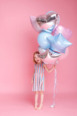 Little girl with pink and blue balloons in a bright dress