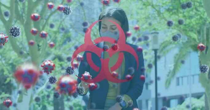 Animation of biohazard symbol and covid 19 cells over woman using smartphone wearing face mask